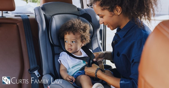 mom buckling son into car seat