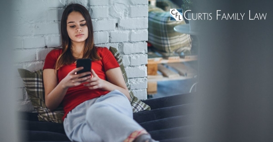 teenage girl sitting on phone at home